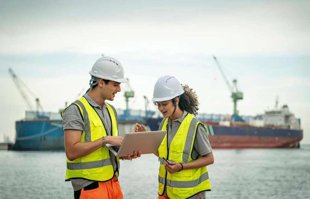 Port workers reviewing logistics updates on a laptop while coordinating port call changes on site