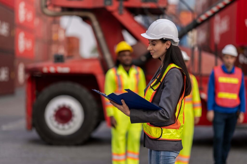 Port worker checking documents during the shipping documentation process with crew and equipment in background