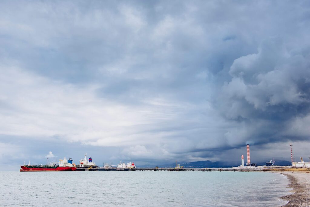 General average port call scene with a vessel at port under storm clouds near an industrial shoreline