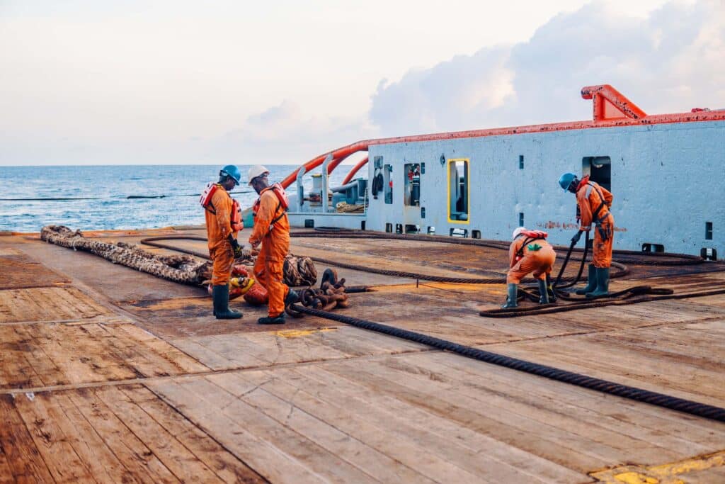 Maritime crew in safety gear managing heavy ropes and deck equipment during operational tasks supporting bunker call coordination onboard a vessel.