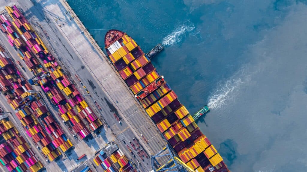 Aerial view of a container ship at port, representing how demurrage management software helps monitor vessel delays and berth timing.