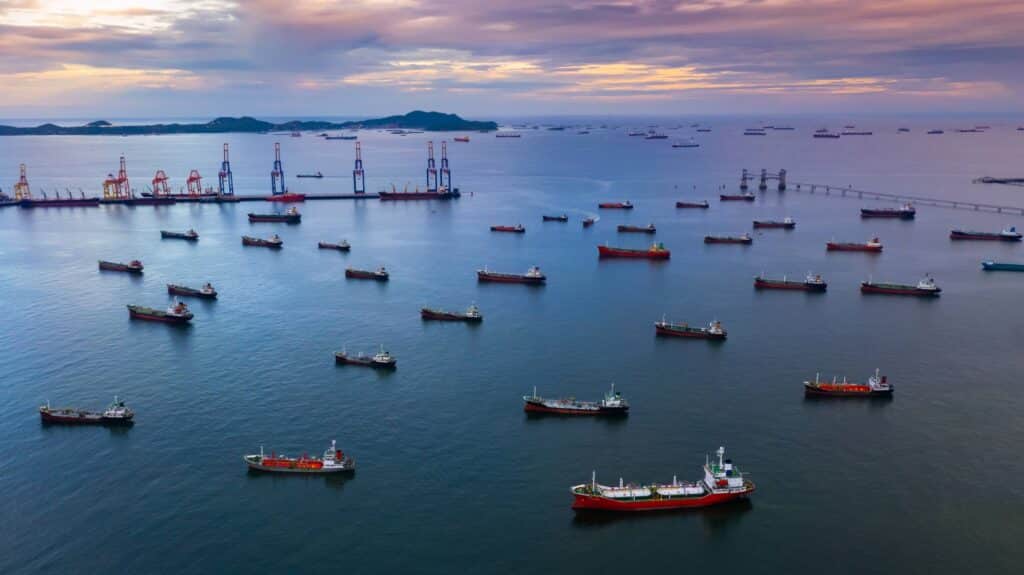 Port vendor reliability challenges shown through multiple vessels waiting near a busy port terminal.