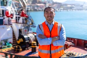 Port worker standing on a tugboat deck, showing the agent and operations coordination supported by demurrage management software.
